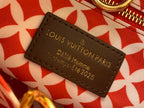 Louis Vuitton leather luggage tag on red patterned fabric with gold lettering