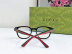 Black Gucci eyeglasses with red-green temples, crossed angle view