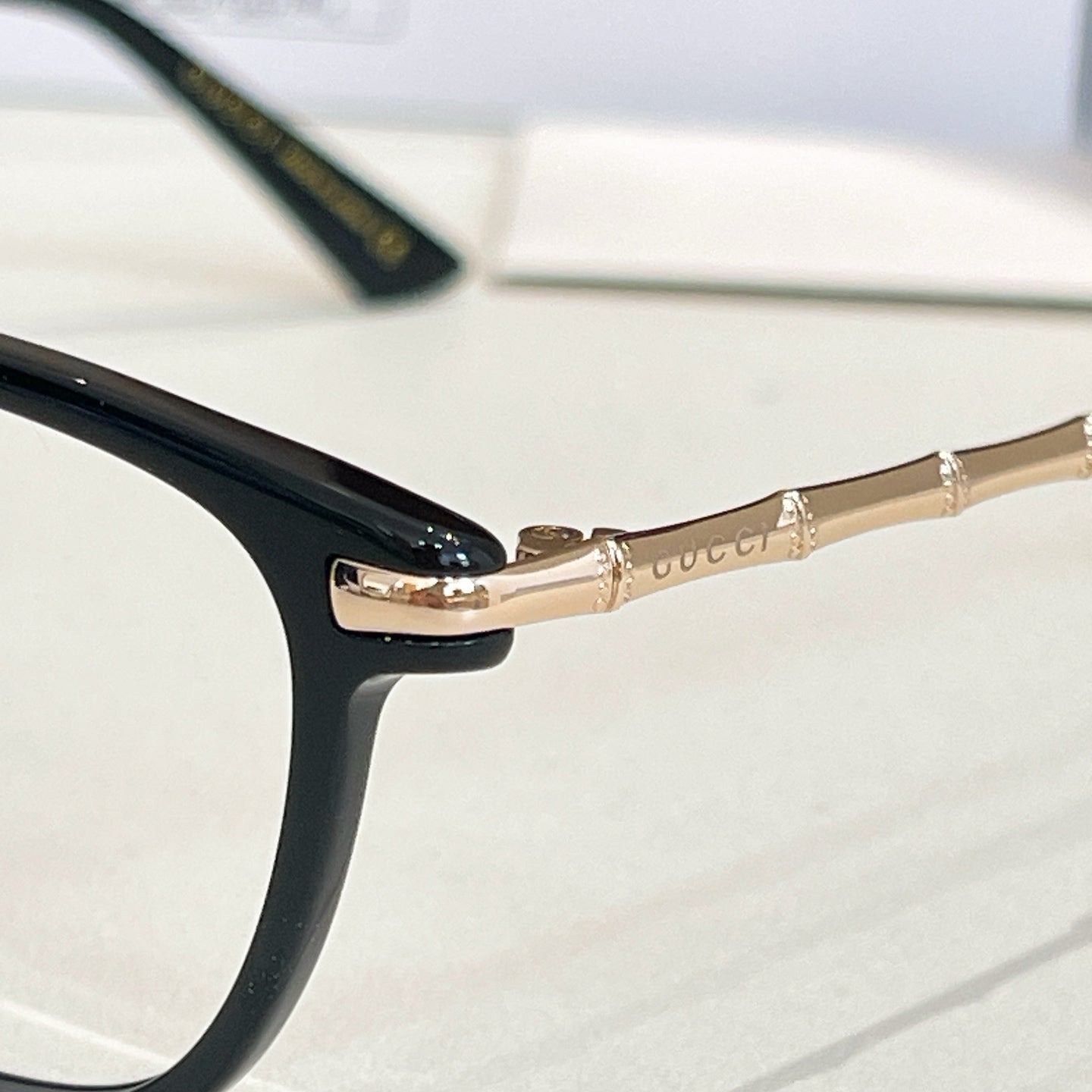 Gucci glasses: close-up of black frame with gold temple and logo detail