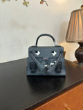 Hermes bag in dark blue with top handle, front flap, and silver emblem hardware.