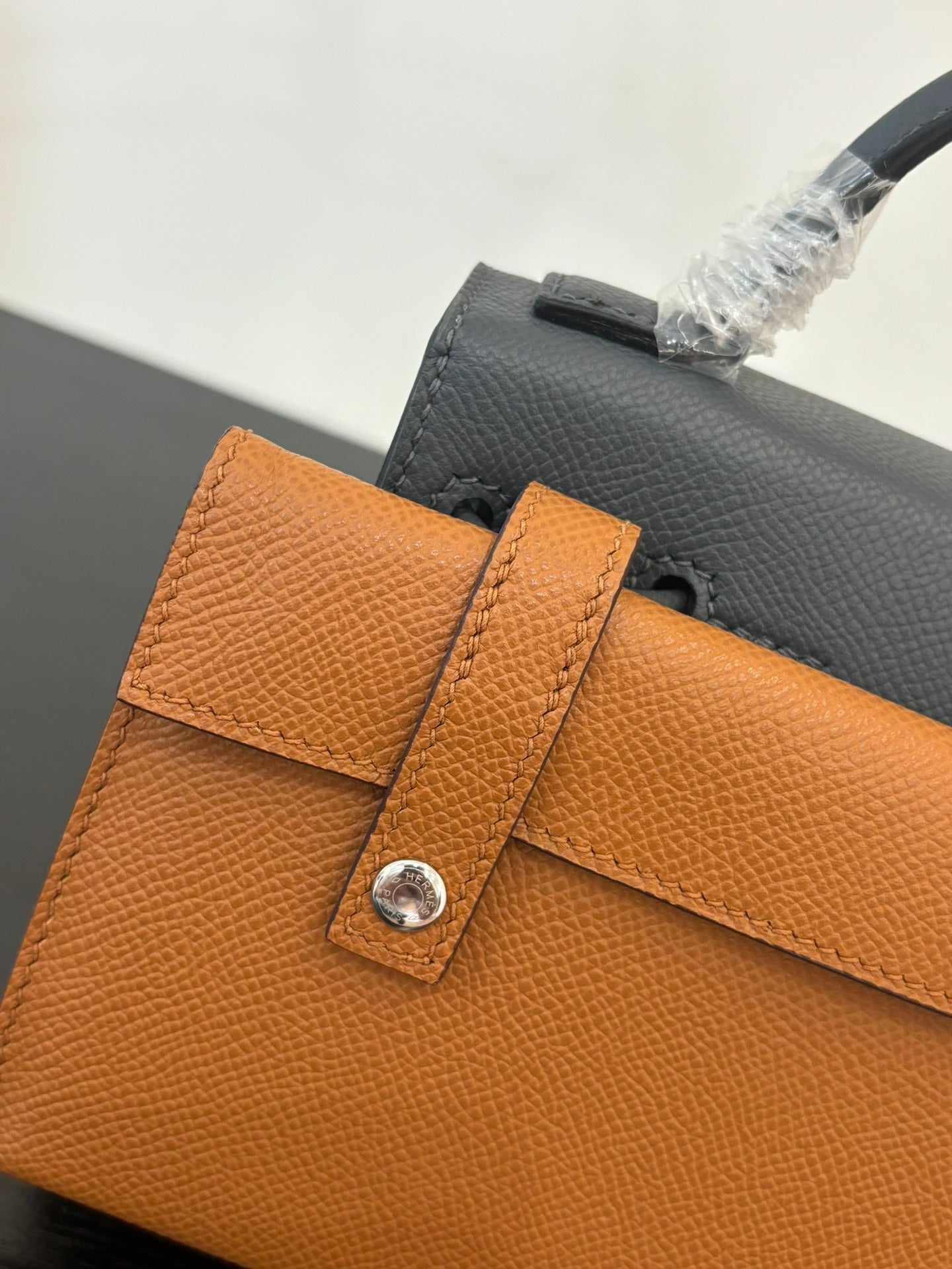 Hermes bag in orange leather with top flap, buckle strap, and metal snap hardware.