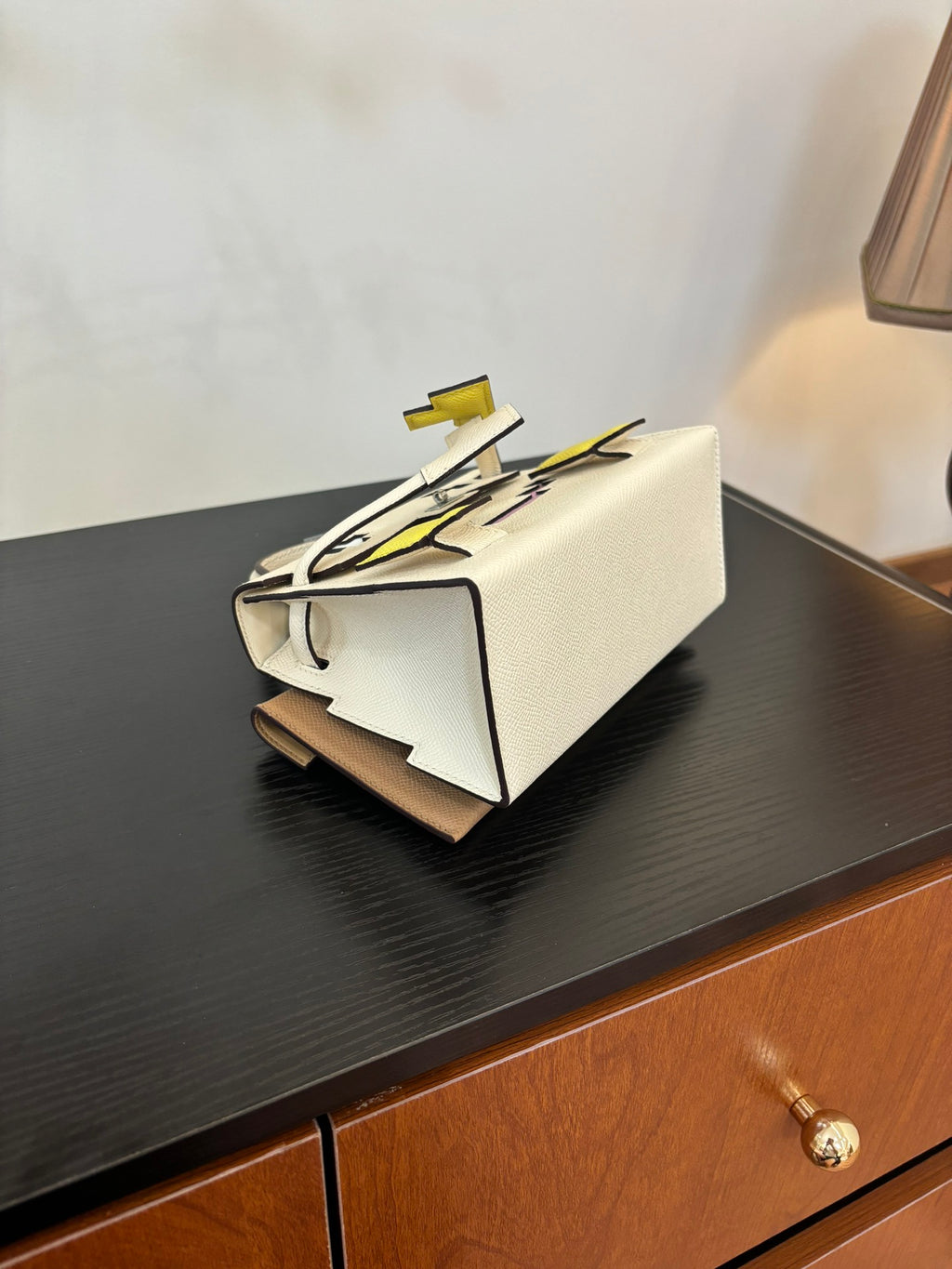 White leather handbag with top handle, layered look with black and yellow strap details