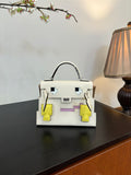 White leather handbag with top handle and geometric patch accents in yellow and purple