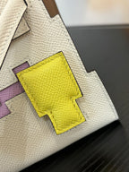 Close-up of white leather handbag with bright yellow geometric patch on flap