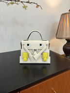 White leather handbag with top handle and geometric patch details in yellow