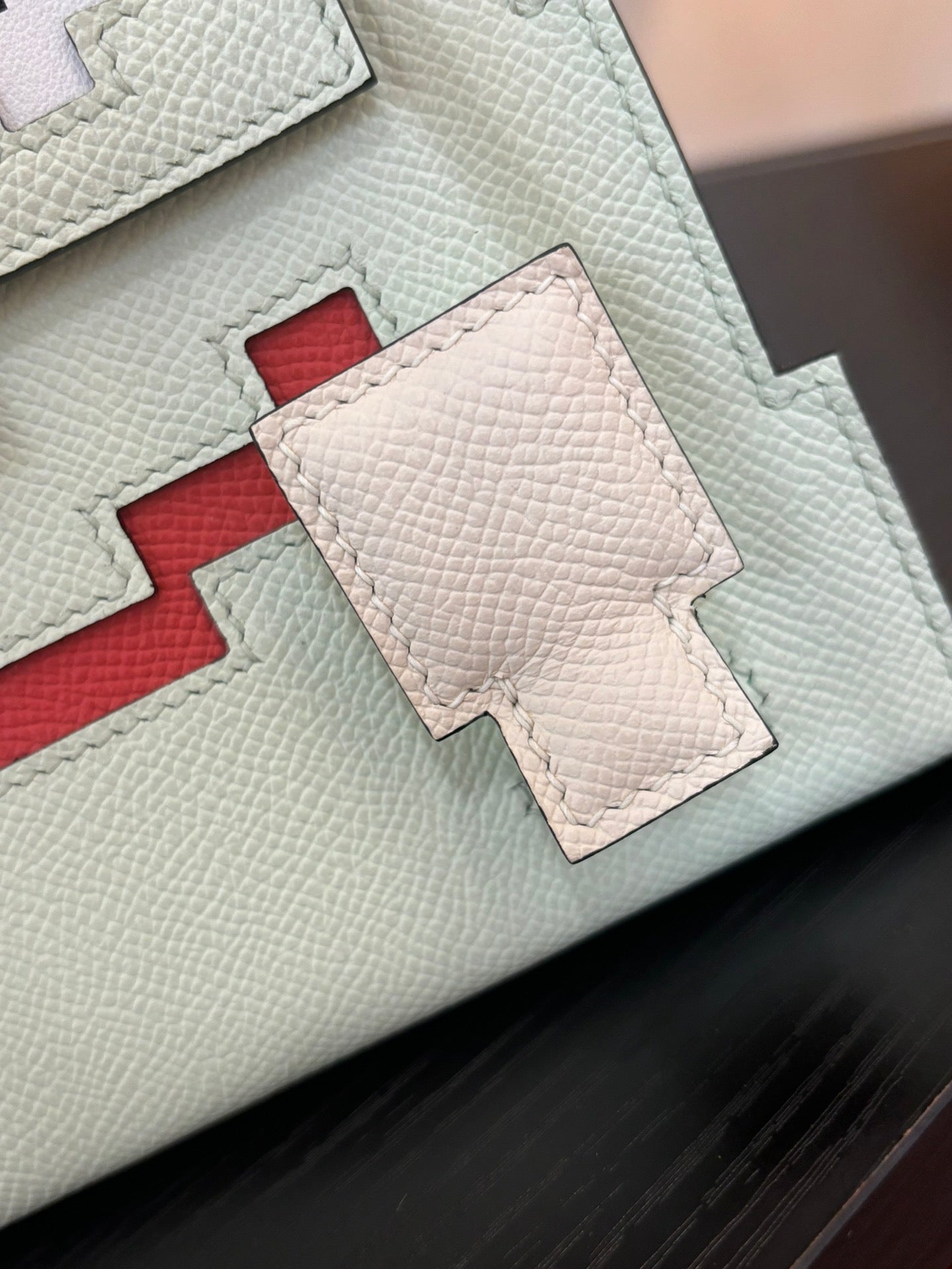 Hermes bag leather close-up with light mint panels and red stitched inset detail