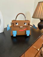 Hermes bag front view in tan leather with multiple blue appliques and small red stripe