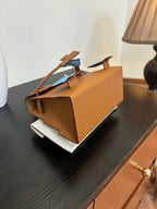 Hermes bag in tan leather with side strap details and top handle, back view