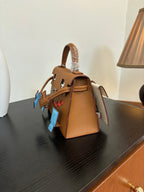 Hermes bag in tan leather with blue accents, side straps, and top handle
