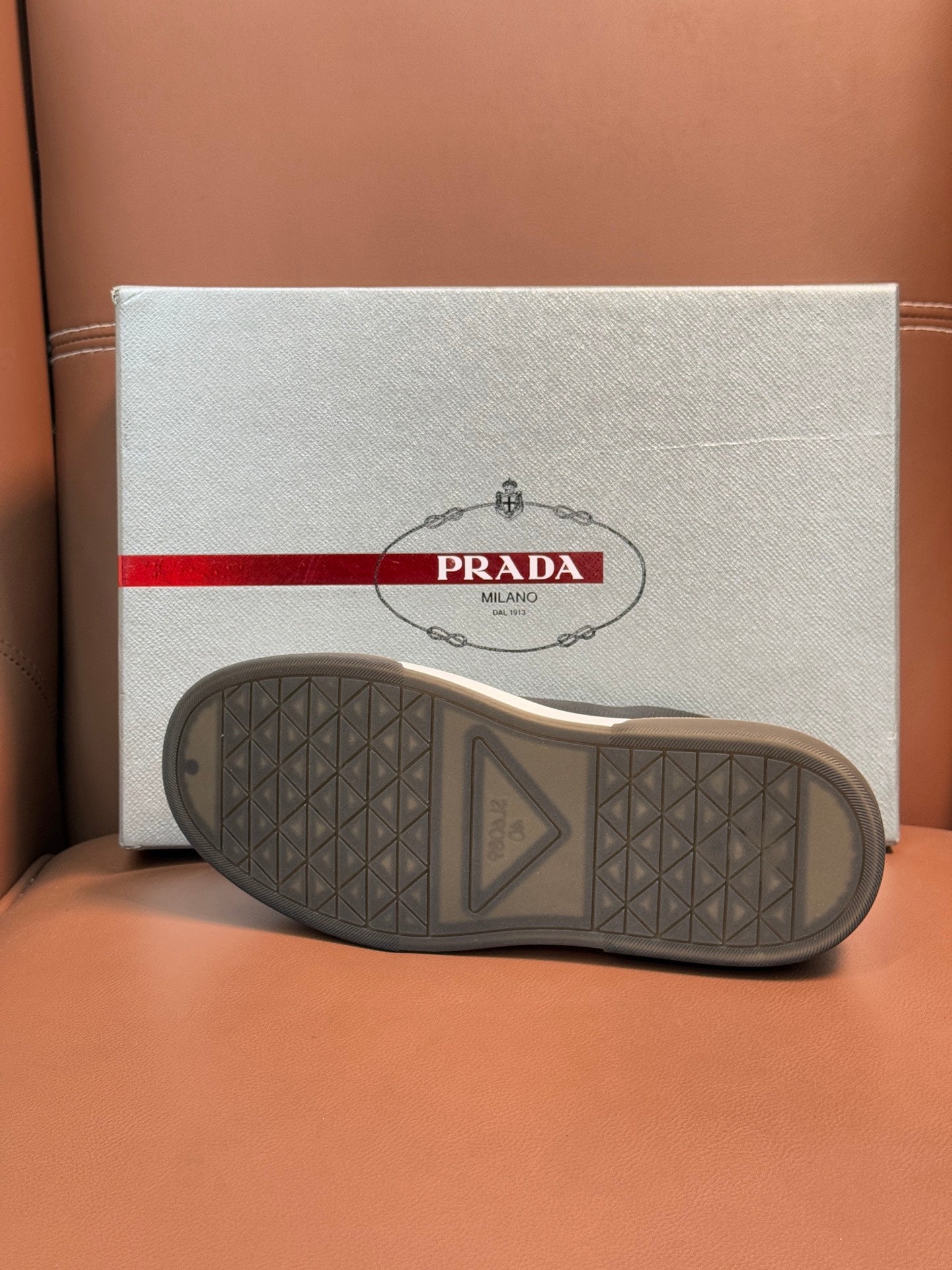 Prada unisex sneaker outsole view, textured rubber tread with dark finish.