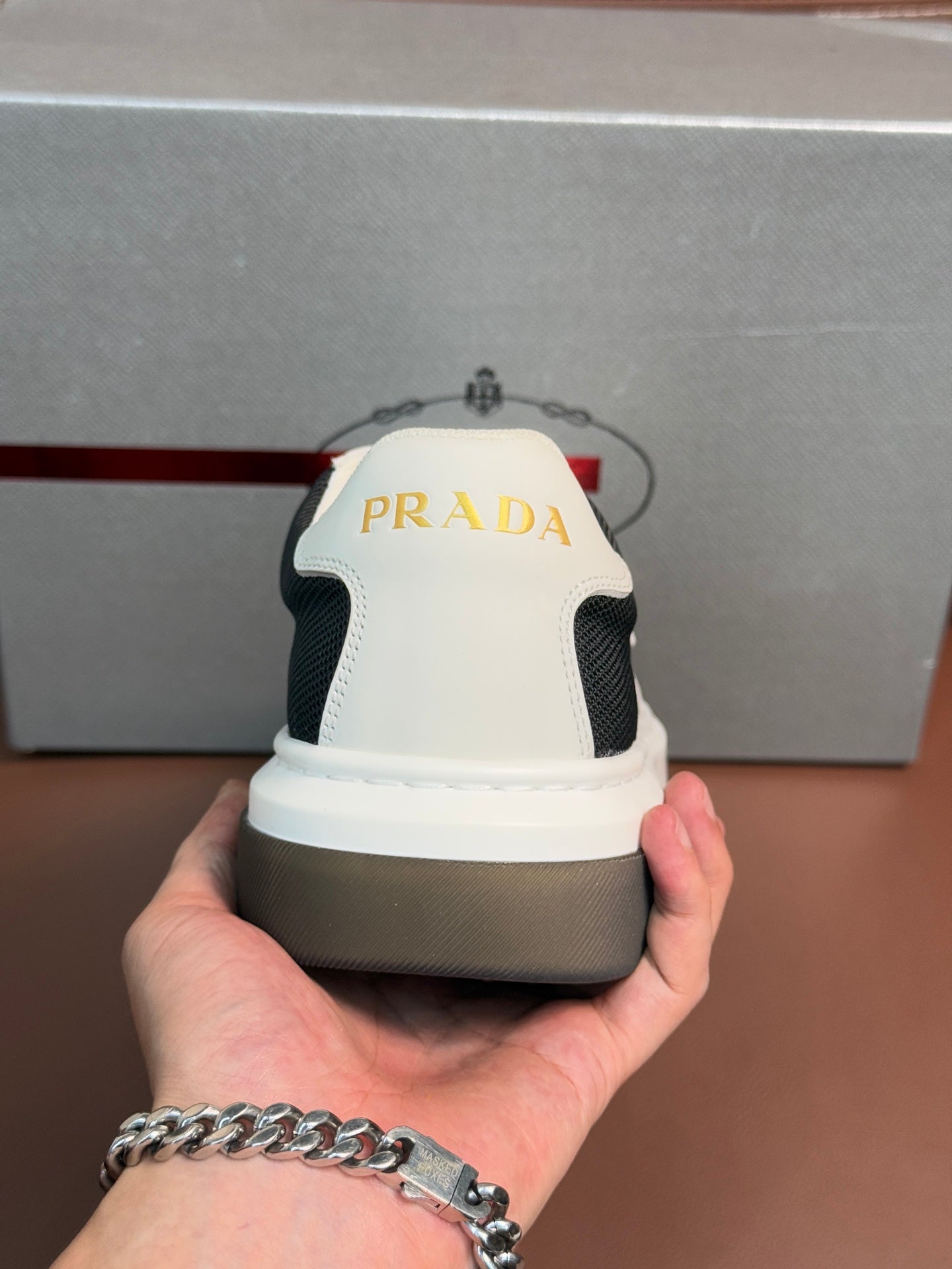 Prada unisex sneaker heel, white back panel with black sides and Prada branding.