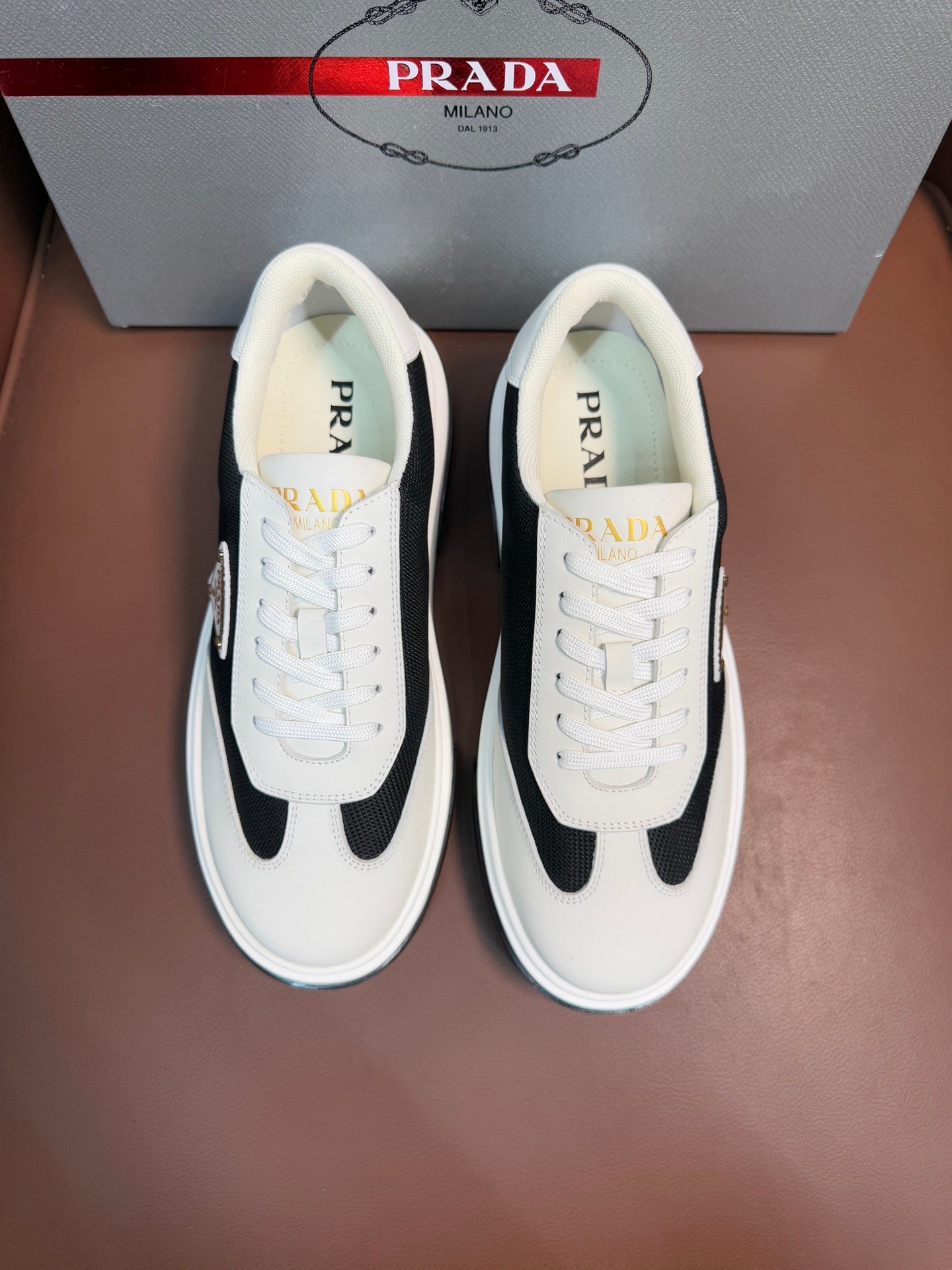 Prada unisex sneakers in white with black side panels, lace-up front, rubber sole.