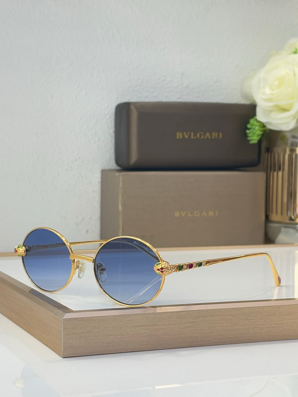 Bvlgari round sunglasses with blue-tinted lenses and gold-tone metal frame, jewel accents