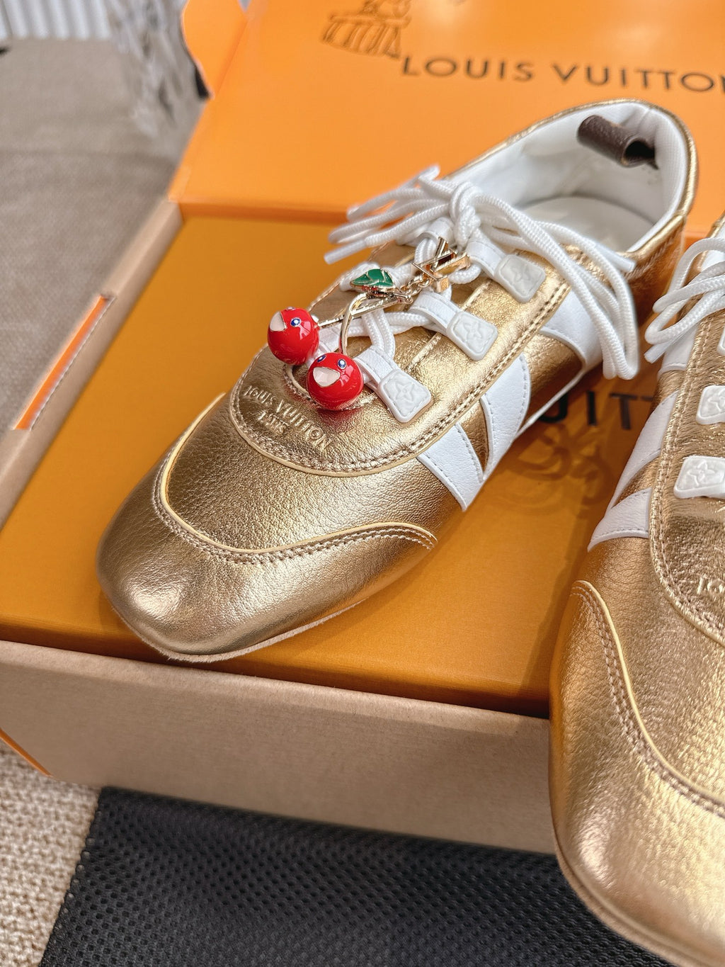 Louis Vuitton metallic gold sneakers with white laces and gold leather upper closeup