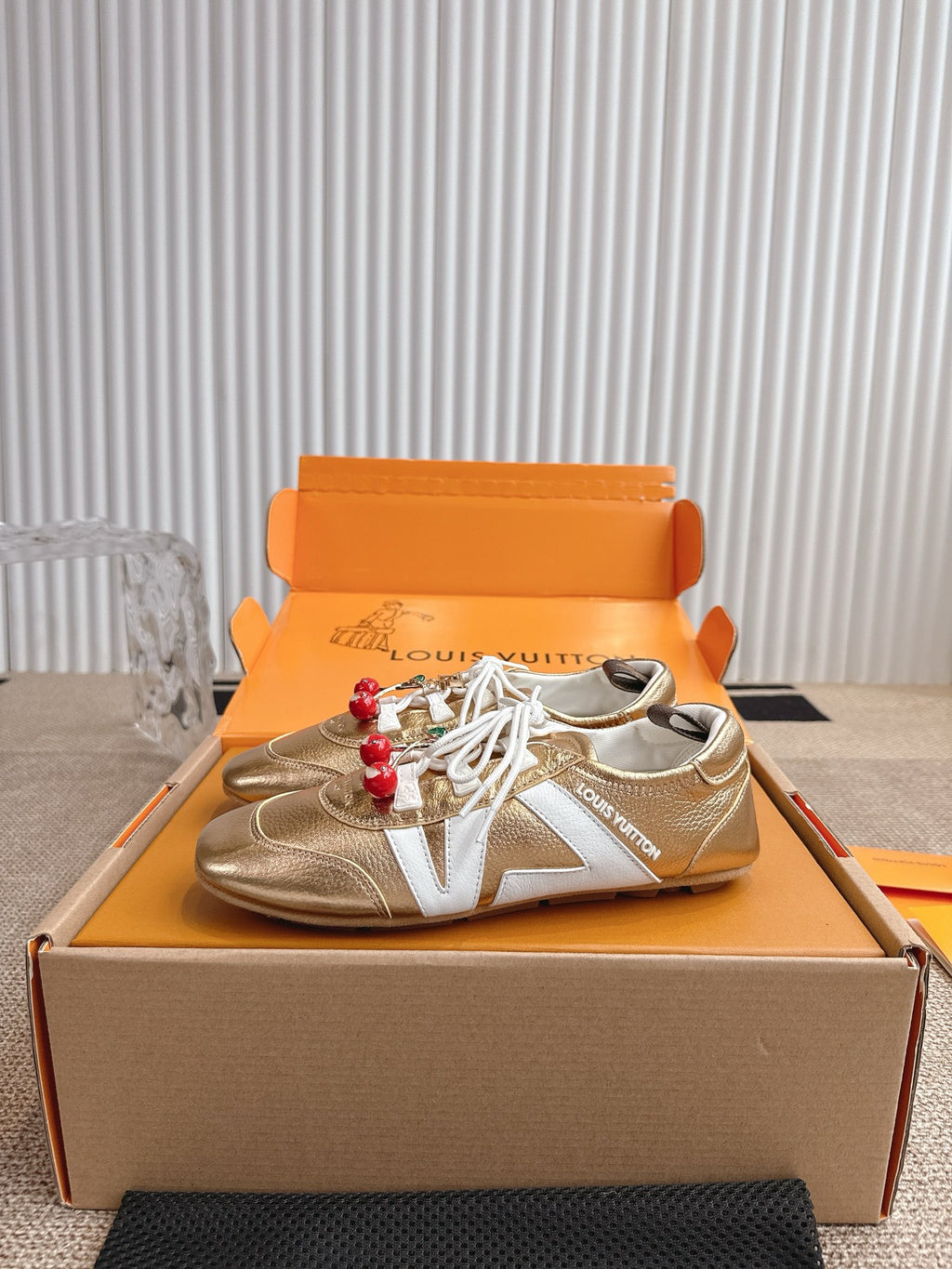 Louis Vuitton metallic gold sneakers with white laces and red cherry keychain charm