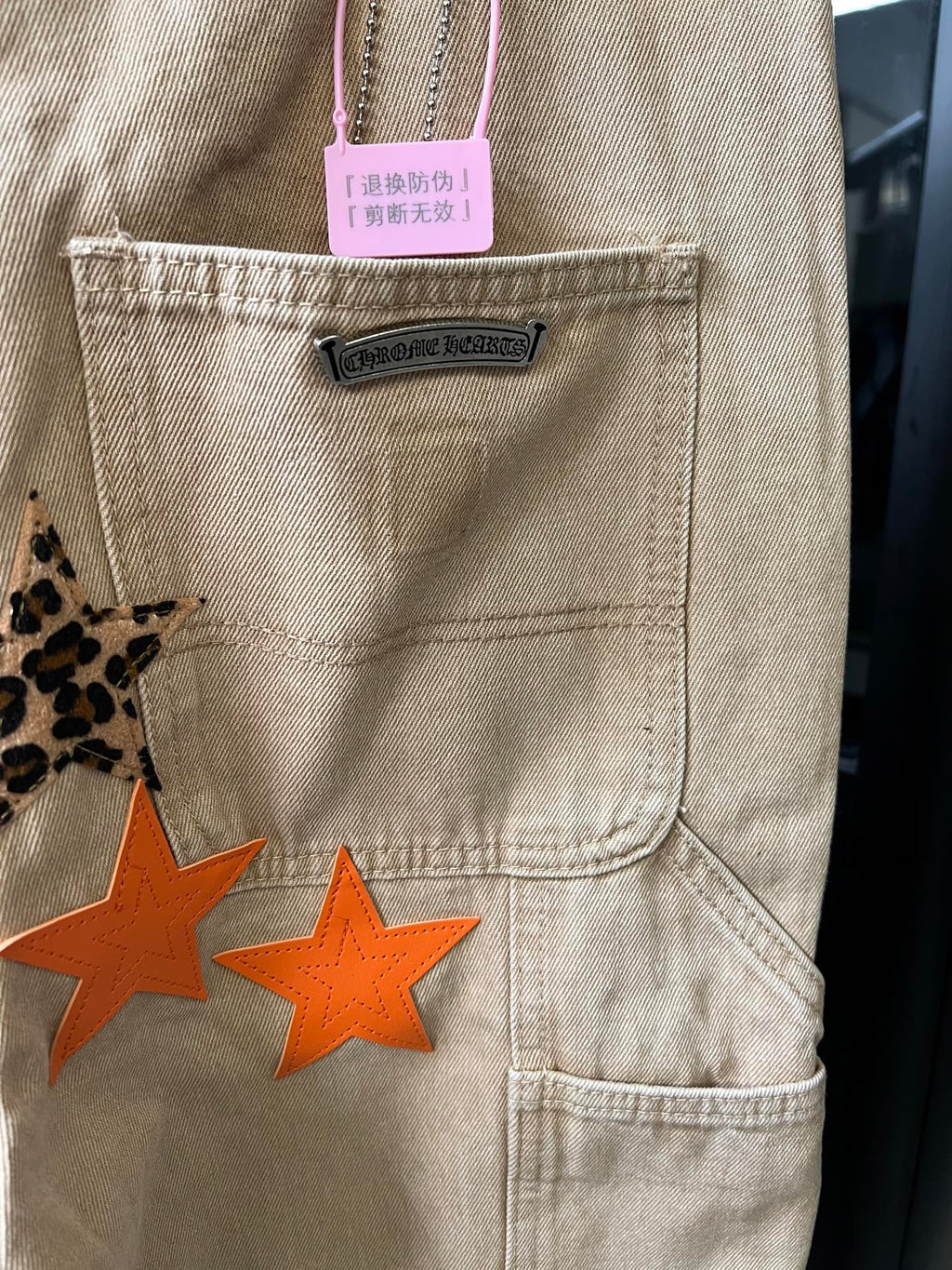 Light khaki pants front pocket with brand label and orange star patch design