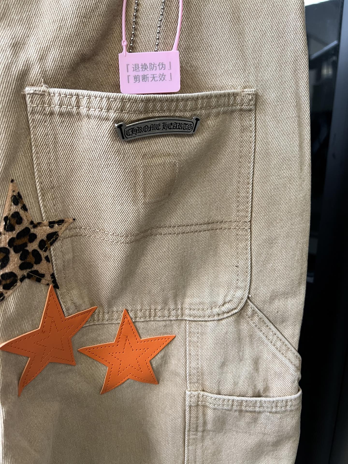 Light khaki pants front pocket with brand label and orange star patch design