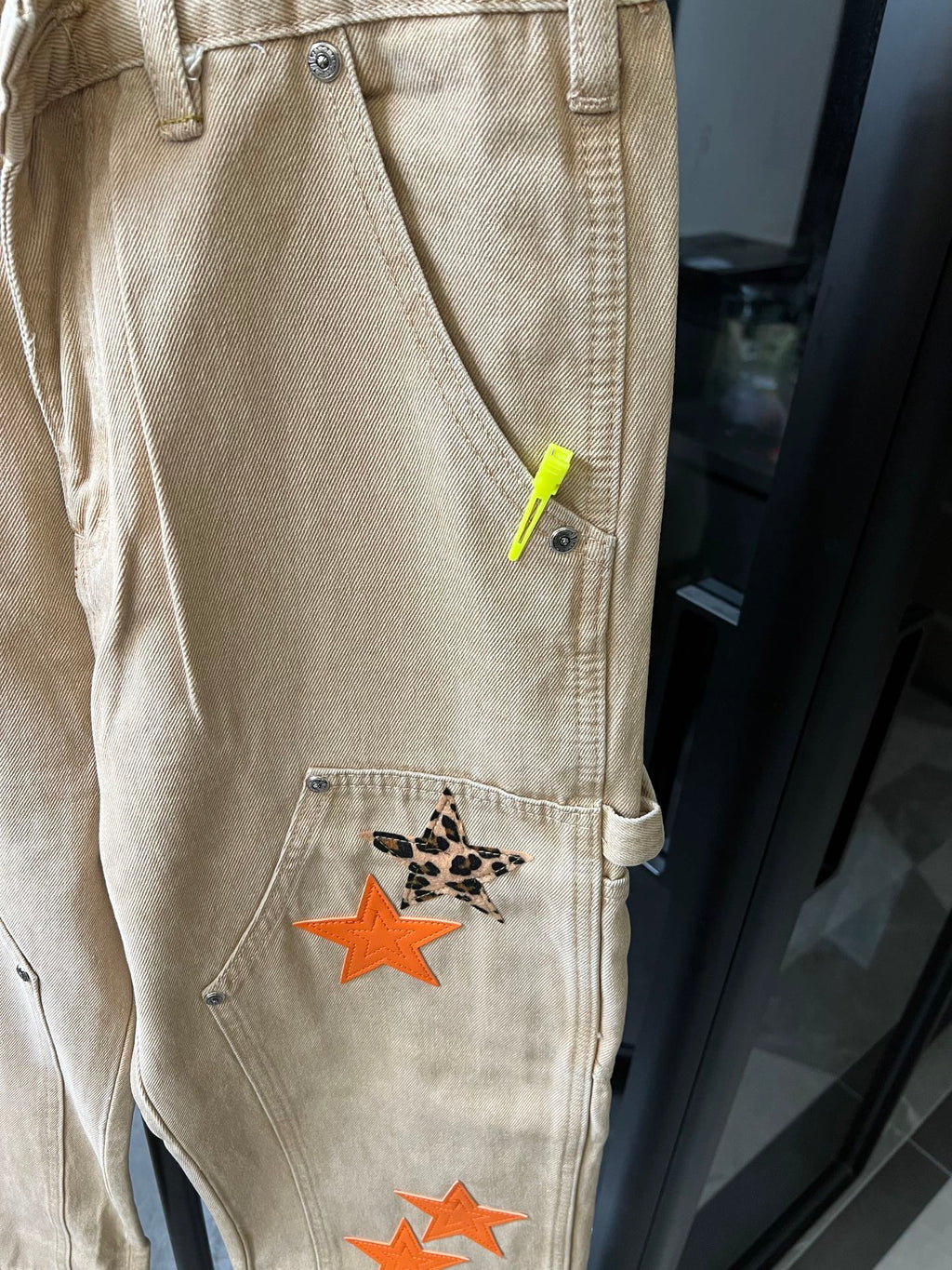 Light khaki pants pocket detail with neon green tag and orange star patch