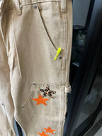 Light khaki pants pocket detail with neon green tag and orange star patch