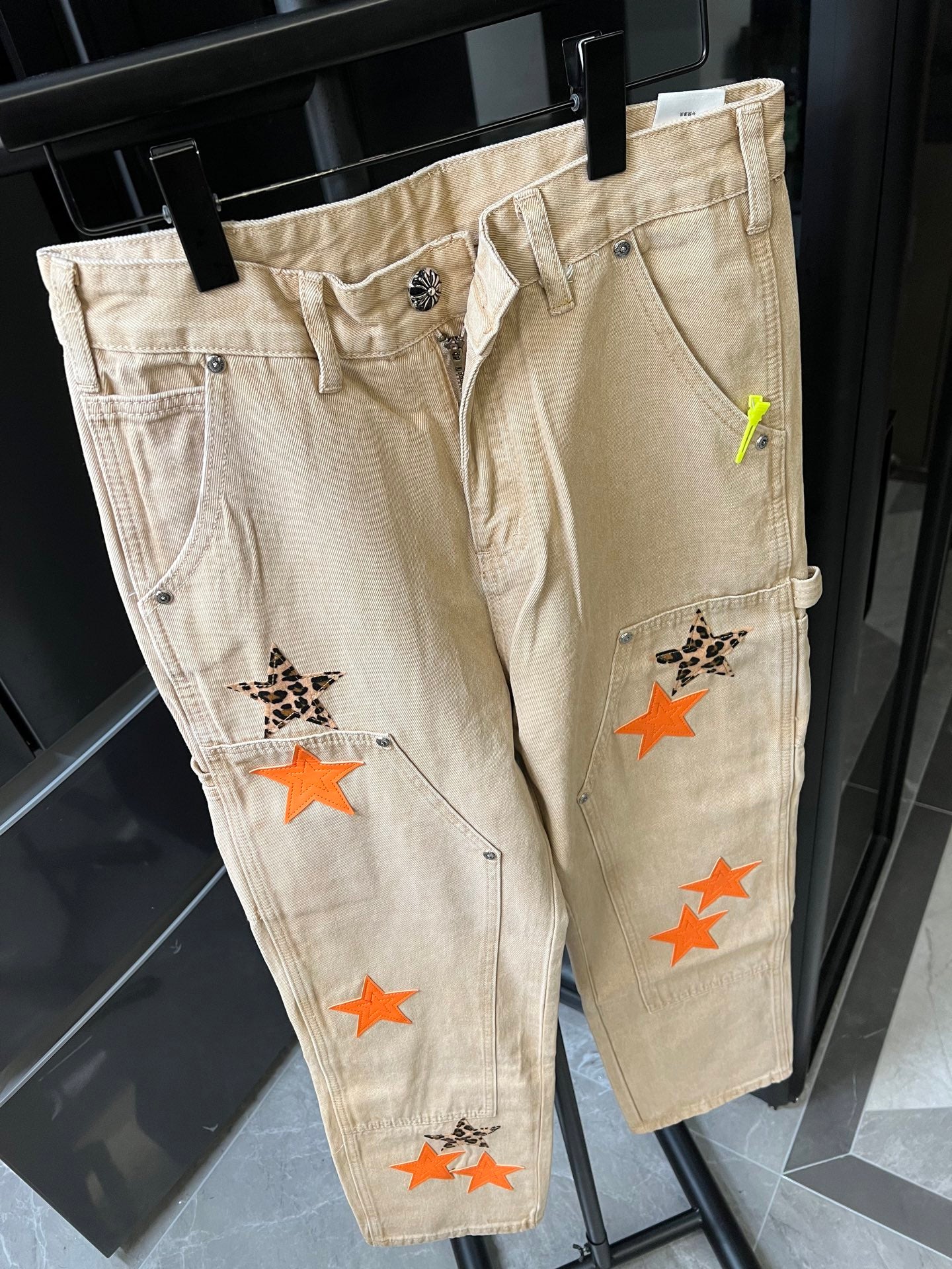 Light khaki denim pants with front patch graphics and slanted side pockets