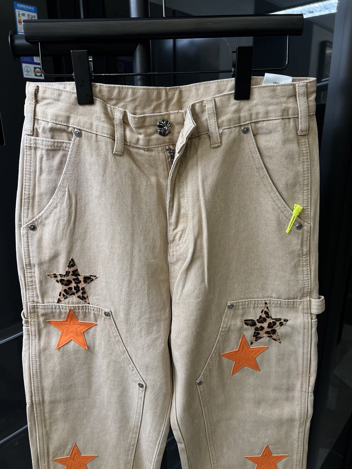 Light khaki denim pants with button fly and orange star patch accents