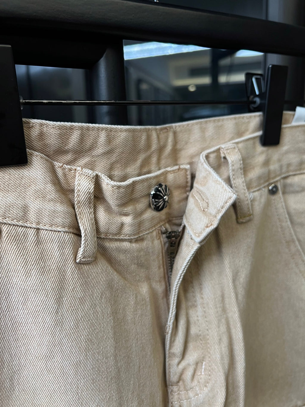 Light khaki waistband and button detail with belt loops and denim texture