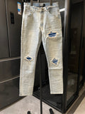 Denim jeans with light wash, distressed rips at knees and matching patched areas