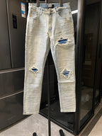 Denim jeans with light wash, distressed rips at knees and matching patched areas