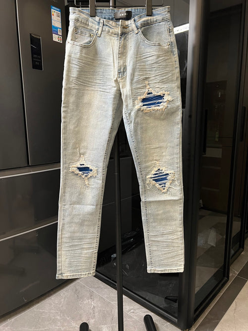 Denim jeans with light wash, distressed rips at knees and matching patched areas