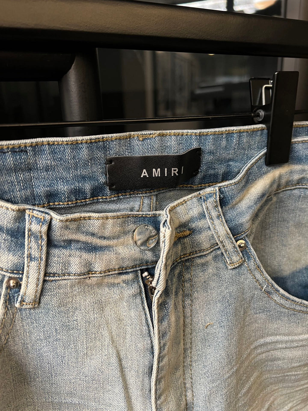 Light-wash denim jeans with waistband button closure and AMIRI logo label