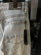 Light-wash denim jeans with front pocket and woven care label near the side seam