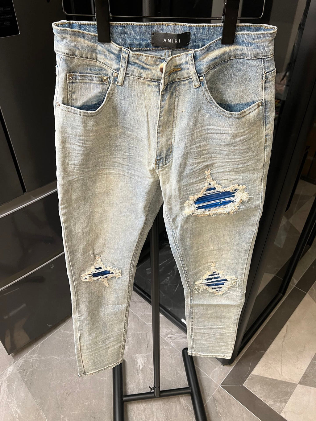 Denim jeans in light wash with knee rips and layered distressed patches