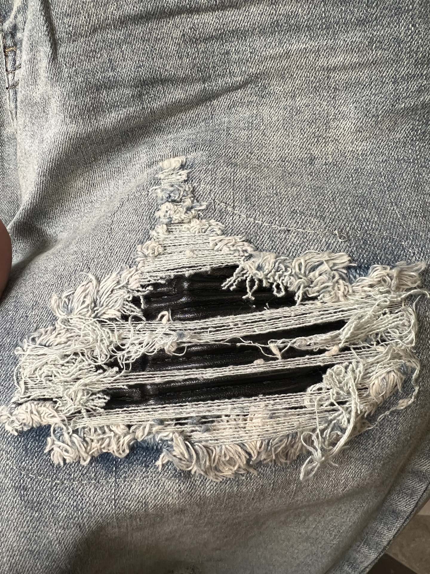 Amiri light-wash jeans with large frayed knee rip and layered distressing
