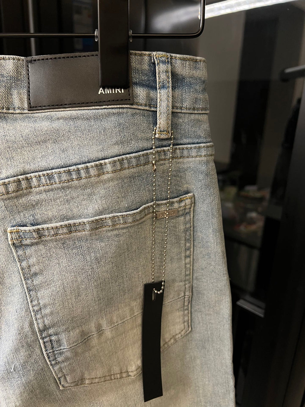 Light wash jeans with a stitched back pocket and a small rectangular repair patch