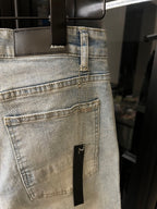 Light wash jeans with a stitched back pocket and a small rectangular repair patch