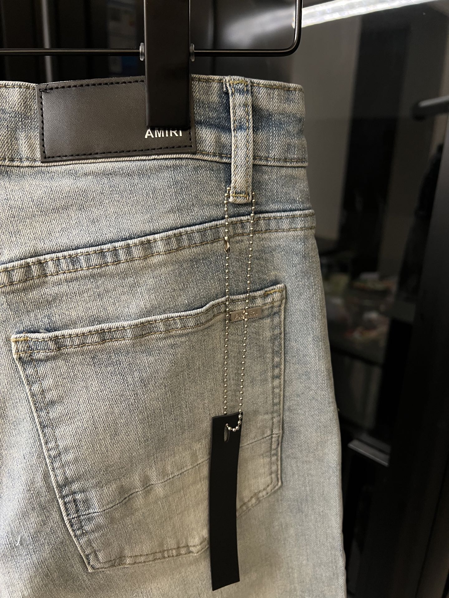 Light wash jeans with a stitched back pocket and a small rectangular repair patch