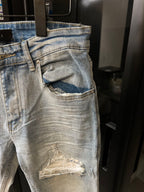 Light wash jeans with a large front pocket opening and a ripped knee patch