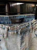 Light wash denim waistband with belt loops, button closure, and distressed front stitching