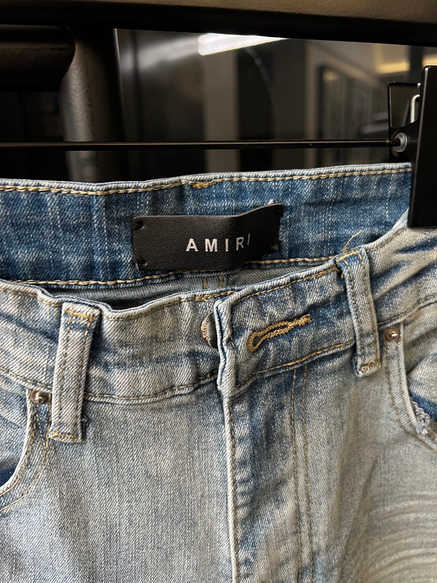 Light wash denim waistband with belt loops, button closure, and distressed front stitching