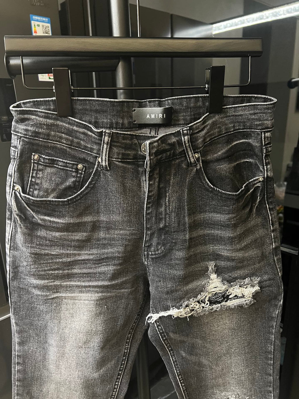 Gray Amiri denim jeans with distressed knee rips and curved pocket stitching