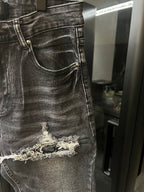 Gray distressed denim jeans with frayed knee tear detail
