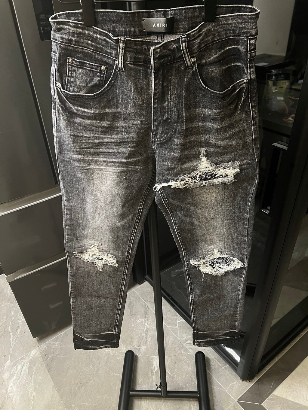 Distressed gray denim jeans with large knee rips and frayed patches