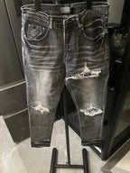 Distressed gray denim jeans with large knee rips and frayed patches