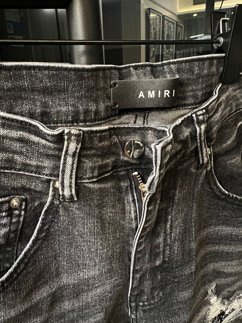 Amiri gray denim jeans with logo waistband patch and visible button fly