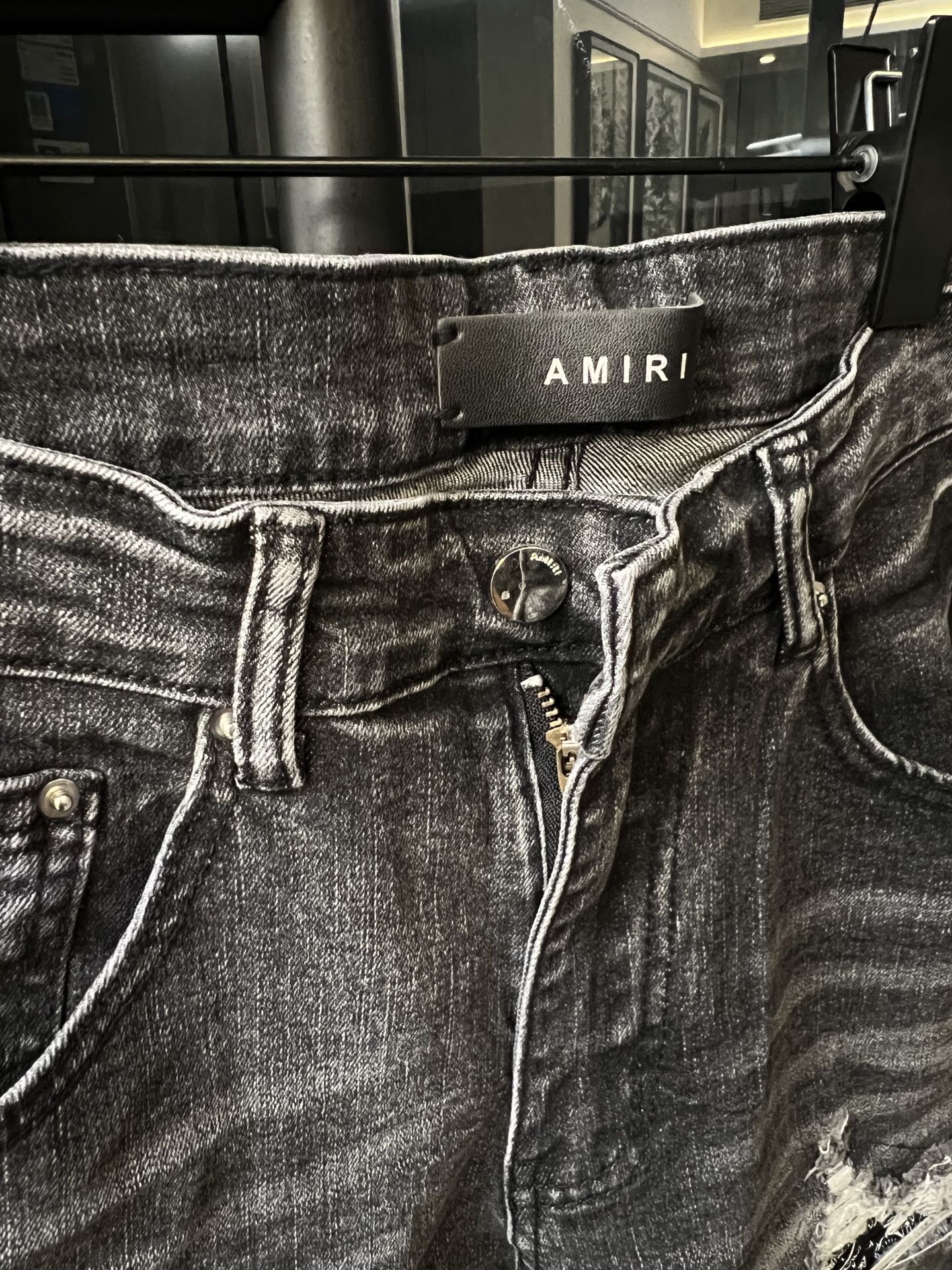 Amiri gray denim jeans with logo waistband patch and visible button fly