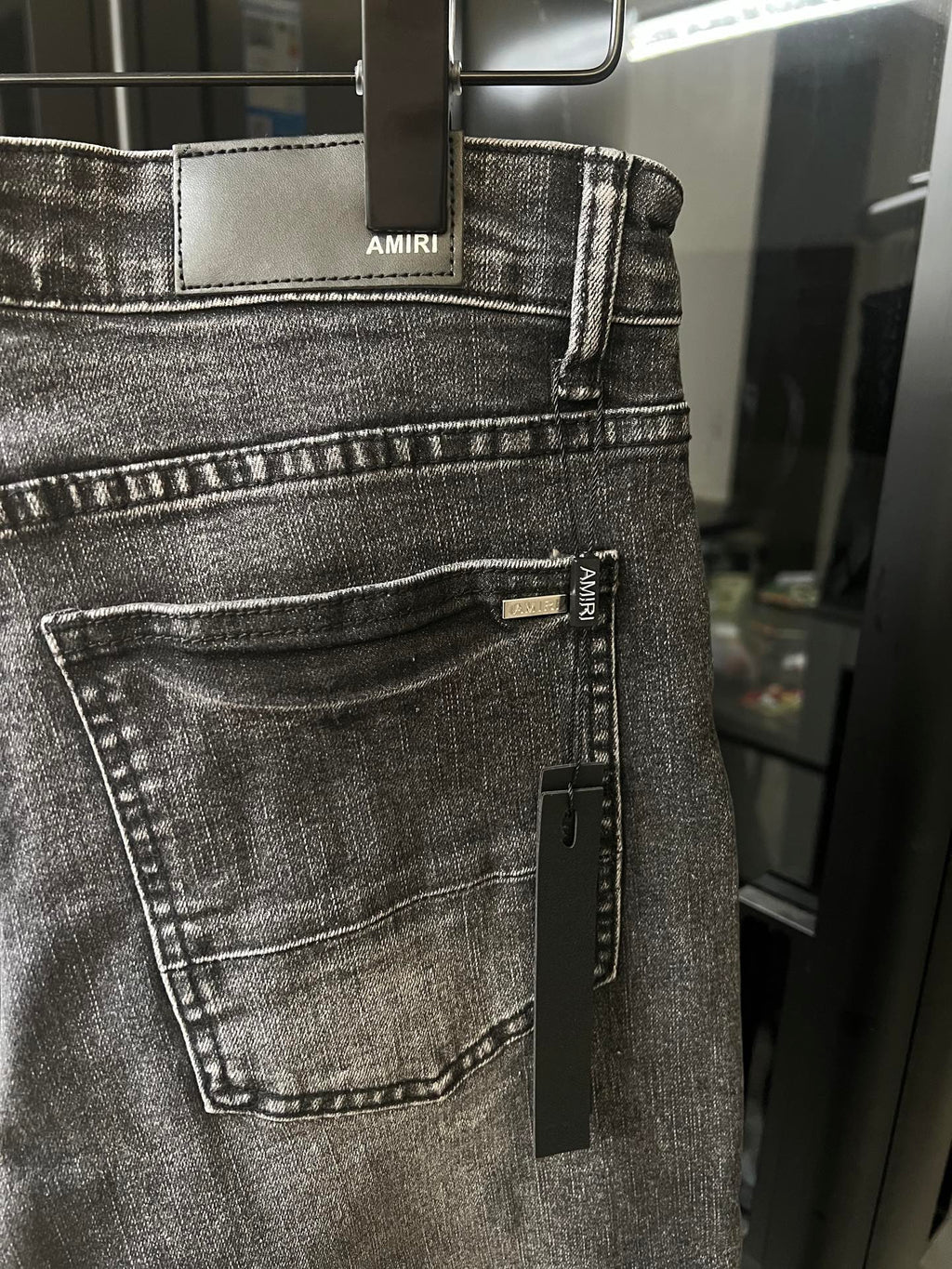Gray denim jeans with front belt loops and AMIRI label on waistband