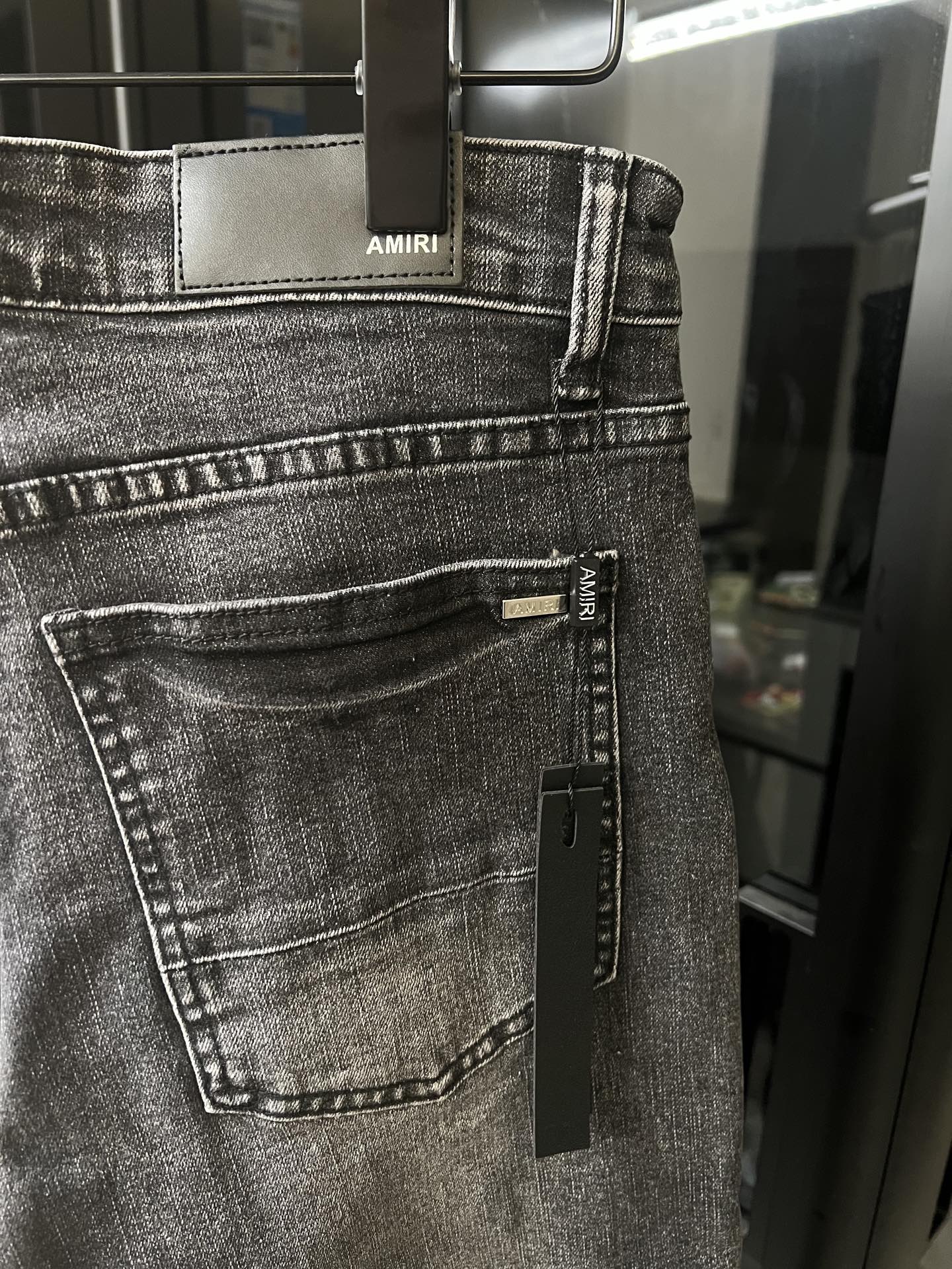 Gray denim jeans with front belt loops and AMIRI label on waistband