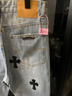Light wash denim pants with back pocket and pink hang tag, black cross patch