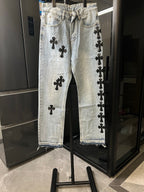 Light wash denim pants with black cross patches, button fly, straight leg