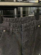 Dark gray denim pants waistband close-up with belt loops and button fly